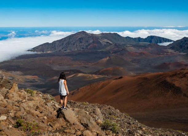 A hiker on the rim of a volcanic crater above the clouds