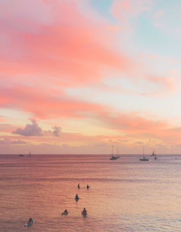 Swimmers in the water at sunset off a Hawaiian beach